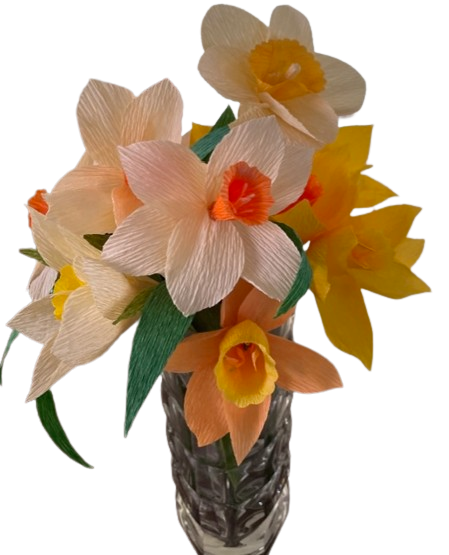 Bloemen van crêpepapier in perzik, crème en geel in een glazen vaas