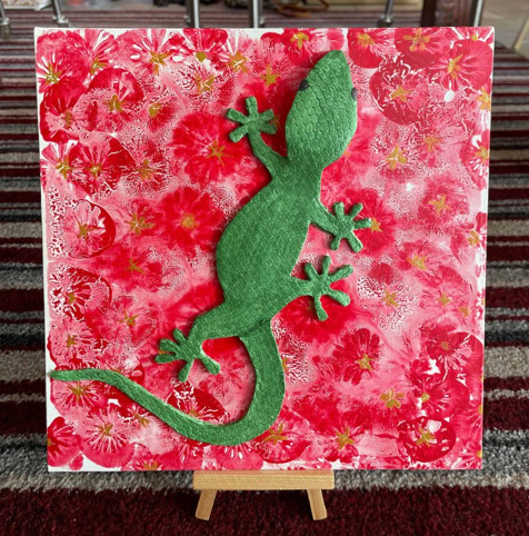 Schilderij van een groene gekko op een rood en roze bloemenpaneel