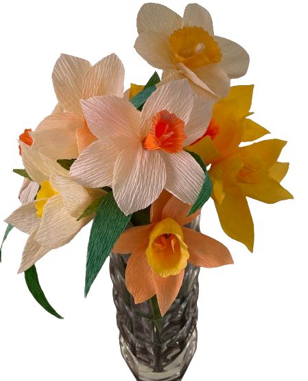Witte en gele narcissen van crêpepapier in een geslepen glazen vaas