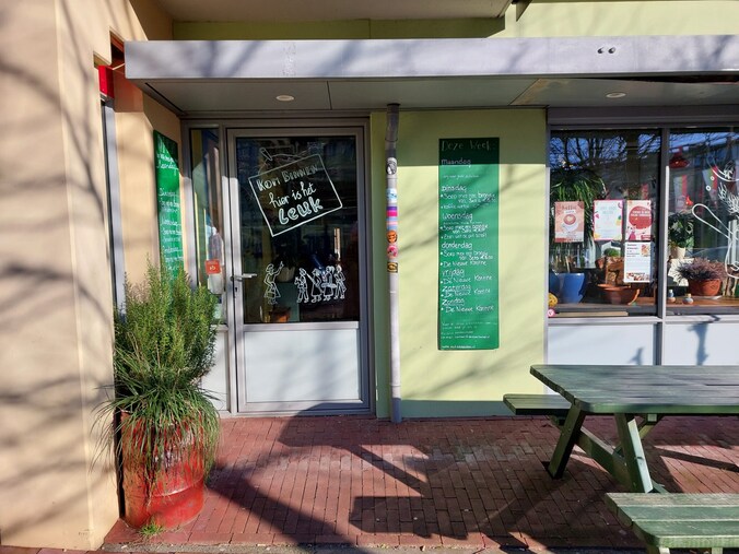Ingang van De Stadskeuken in Arnhem met groen krijtbord en picknicktafel