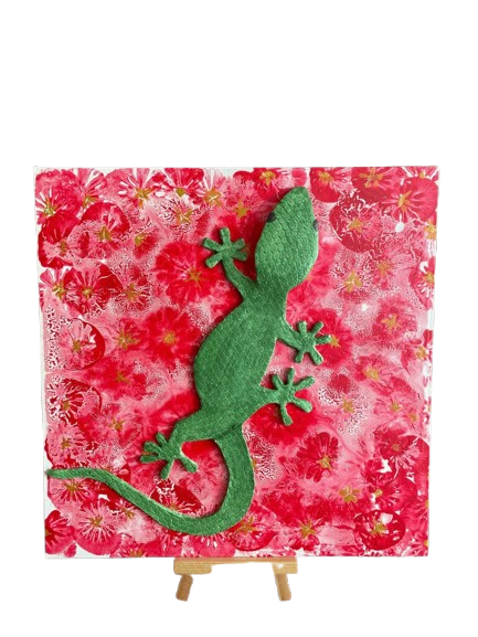 Kunstwerk met een groene gekko in reliëf op een rood-wit bloemenvlak